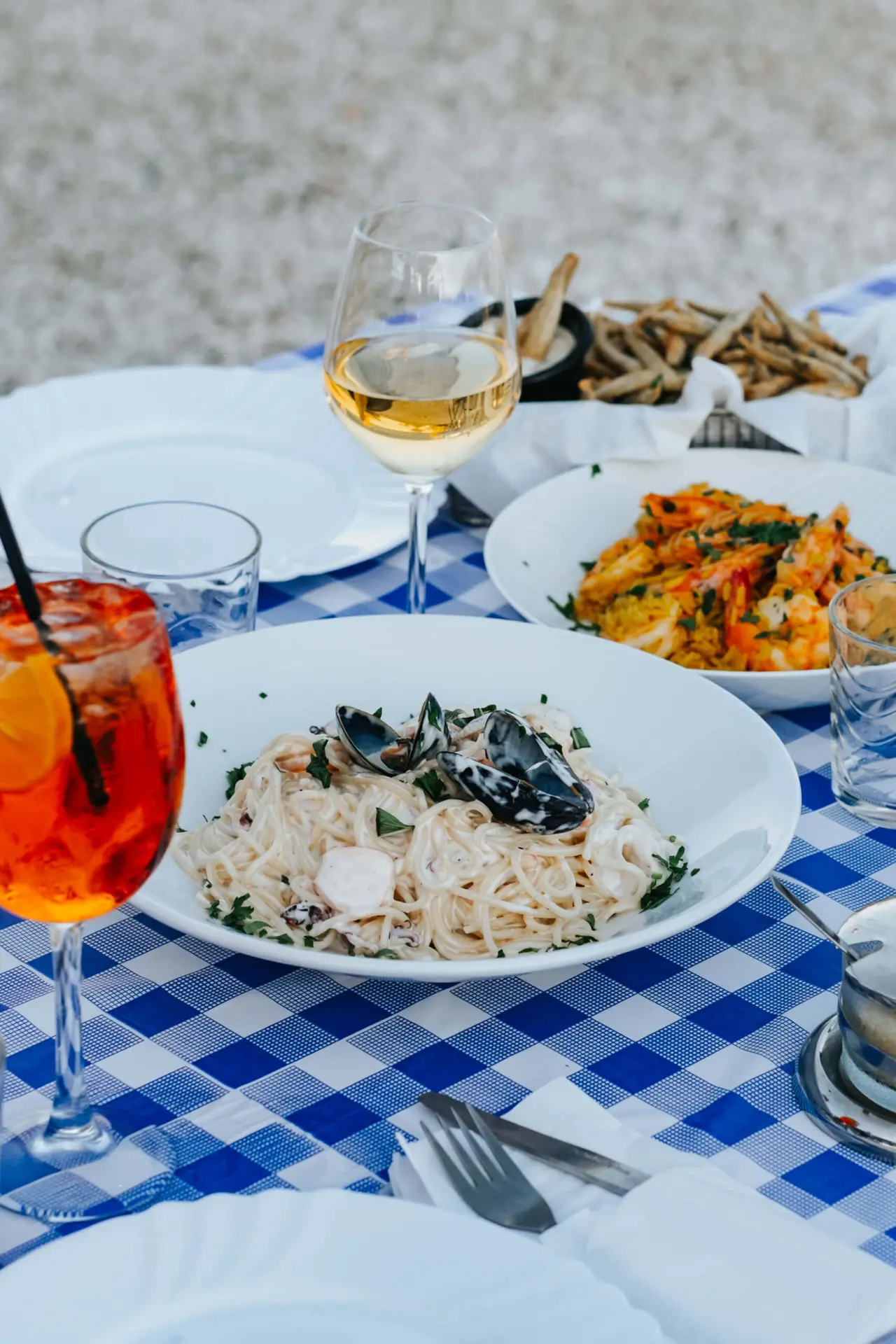 Seafood pasta, fried fish and wine on a blue checked tablecloth at Alieutiko Katafygio